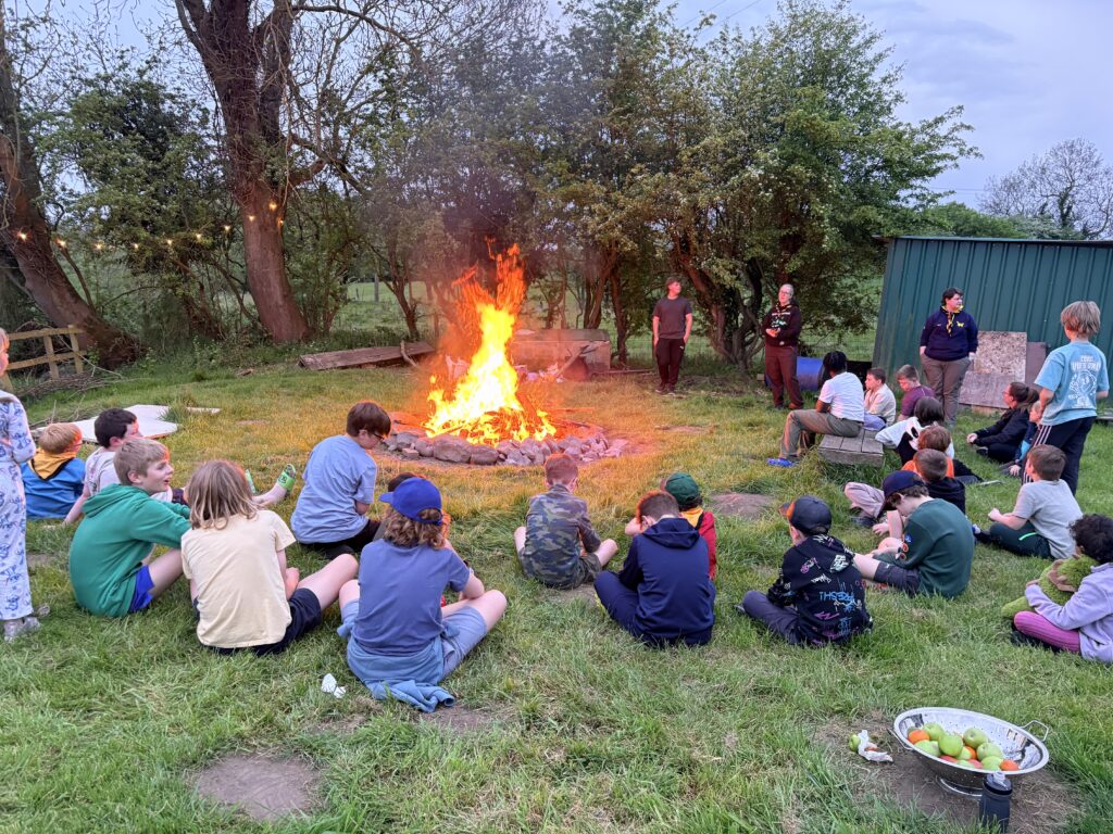 Group of young people sitting round camp fire at Aldwark